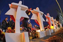 People gather around candlelit memorials.