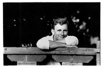 black-and-white photo of Edmund White smiling, in a white shirt