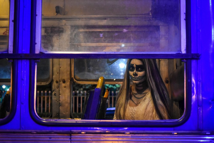 A person dressed in a ghostly costume poses inside a bus.
