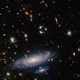 A James Webb Space Telescope picture of a nearby galaxy, spiral and sparkling, along with many smaller galaxies in the dark background