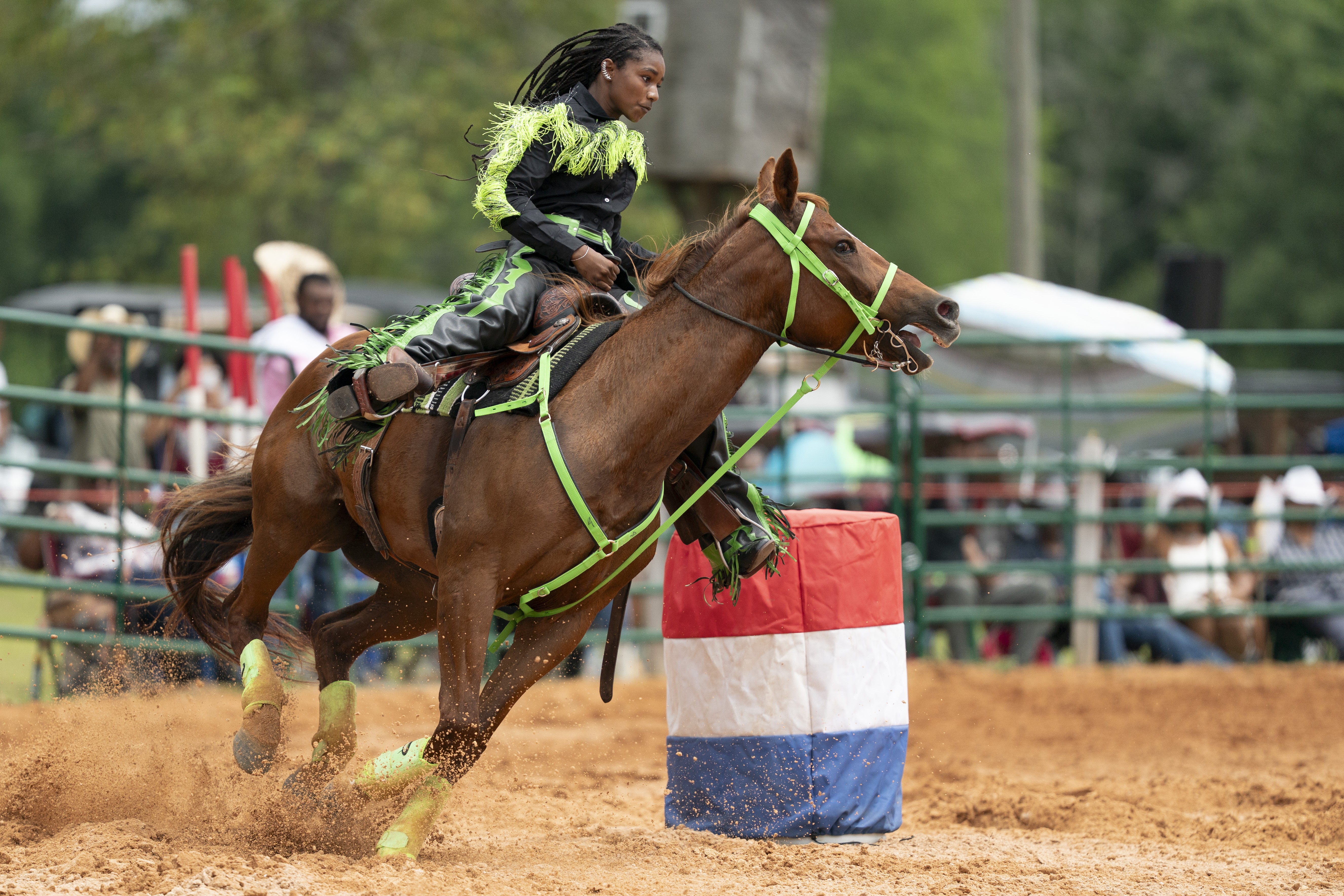 An exhibitor rides a horse around barrels at a festival.