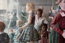 A young black girl and her mother look at a display case filled with white mannequins.