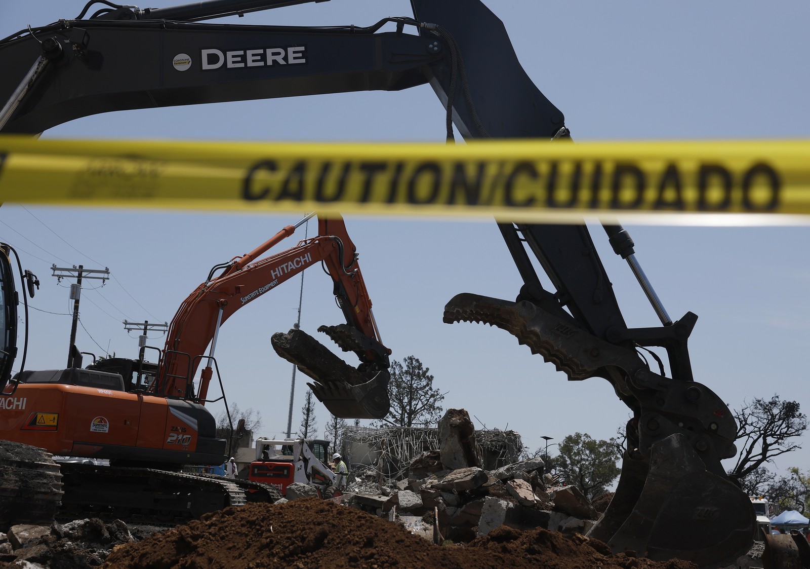 A demolition crew uses excavators to tear down a business destroyed by a fire.