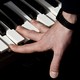 a hand pressing down on the keys of a piano