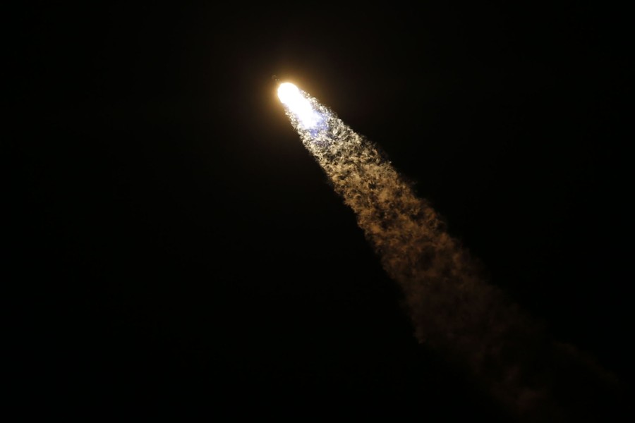 A rocket leaves a bright plume of exhaust as it launches into the night sky.