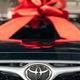 An image of a Toyota car with a red bow on the hood.