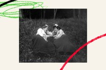 Two female friends laying in the grass, talking and smiling