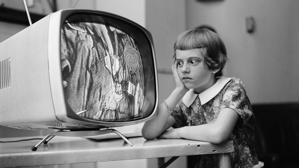 A vintage photo of a young girl staring at a TV screen