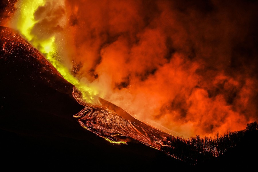Lava flows down a slope at night.