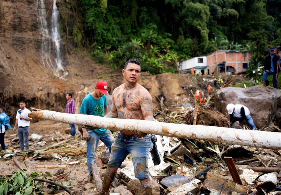 A group of people work to remove debris from the scene of a mudslide.