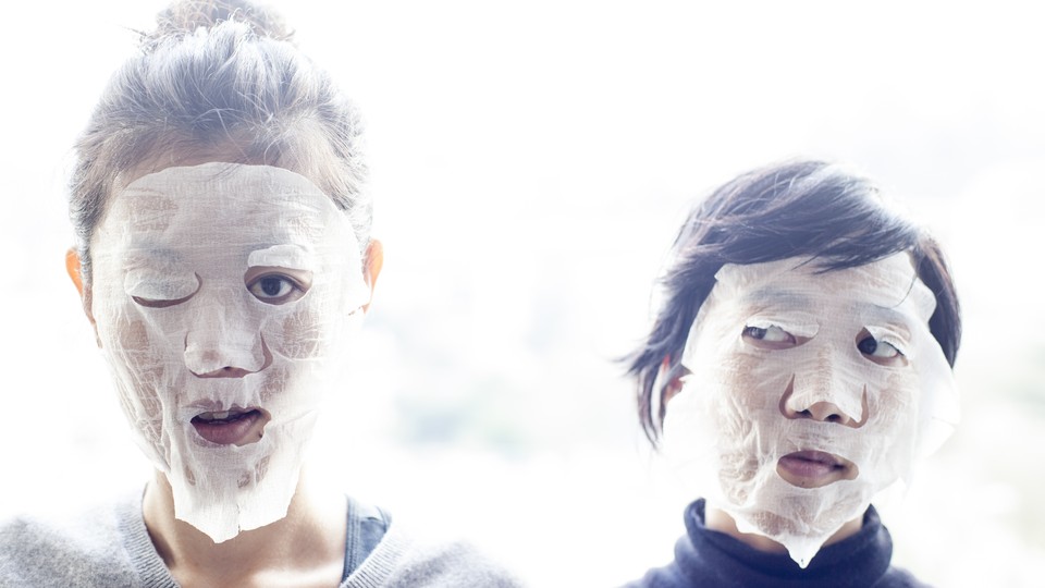 Two women wear skin-care face masks.