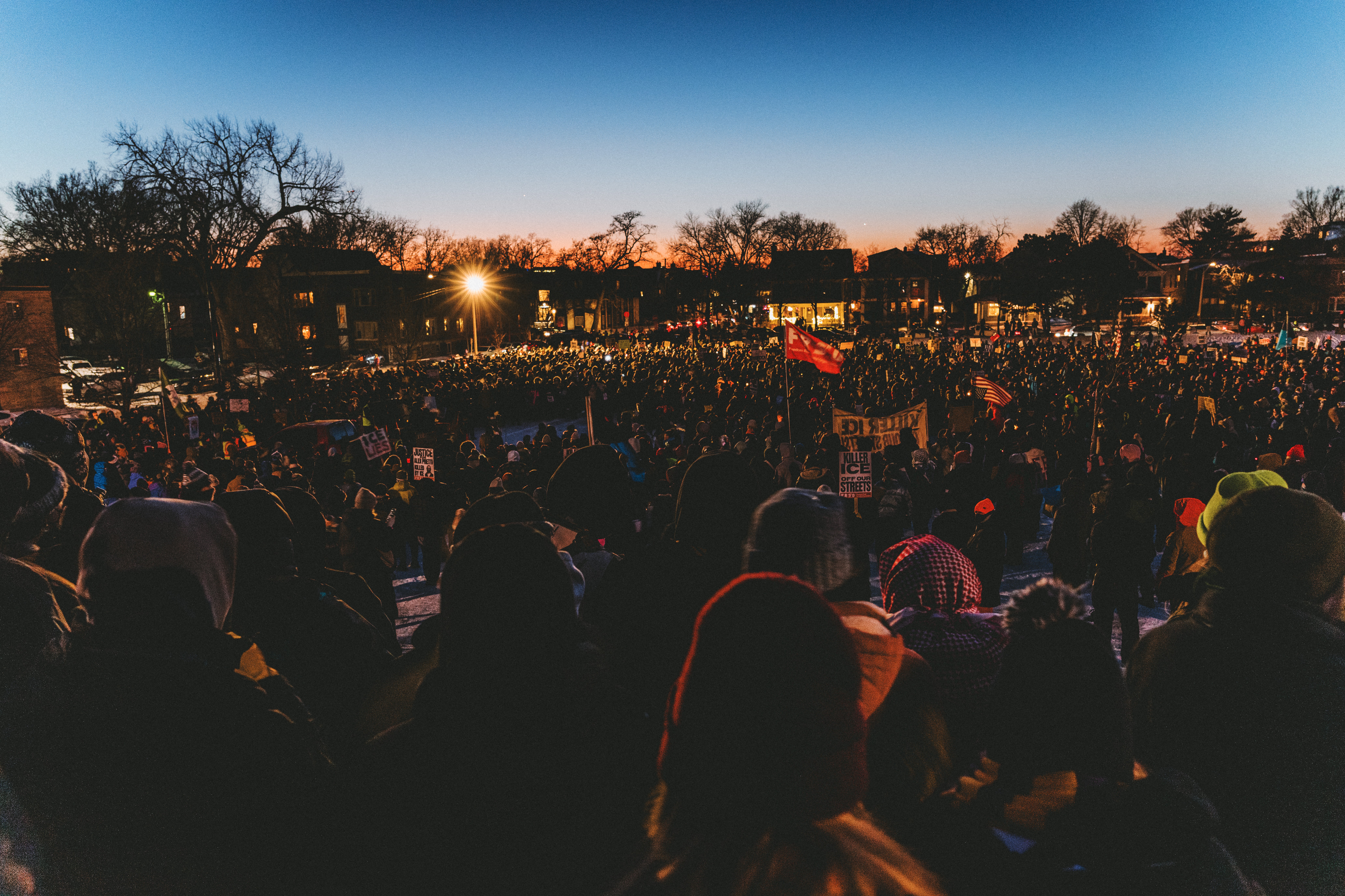 A large group of mourners are seen in the evening light at a vigil