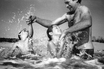 a man struggles as he plays with two children at the beach