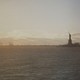 Sunlight reflects on the water across from the Statue of Liberty