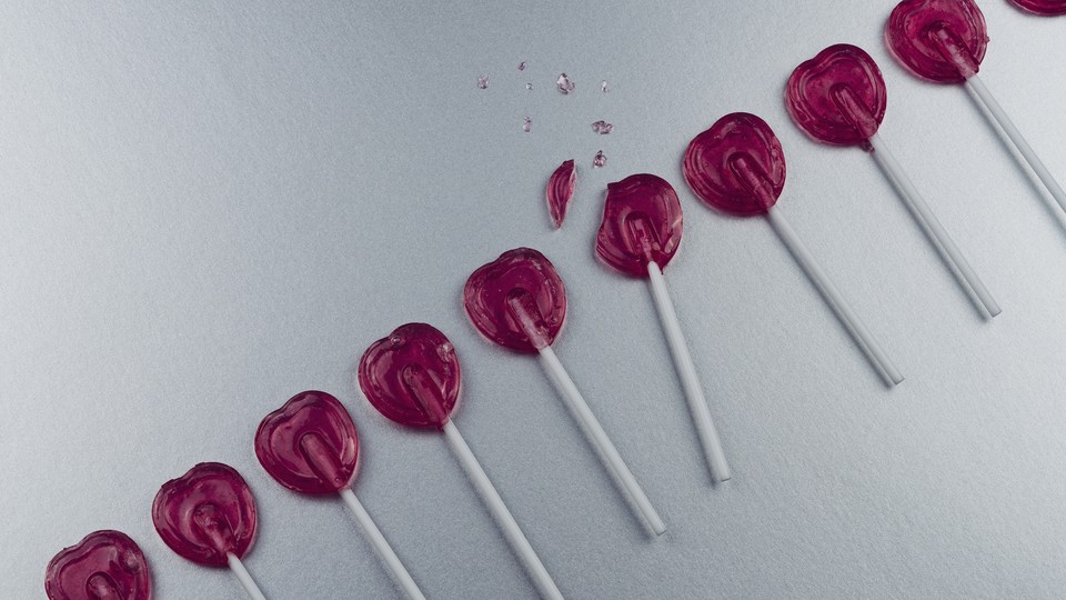 a photo of heart-shaped lollipops in a row, with one that's broken in the middle