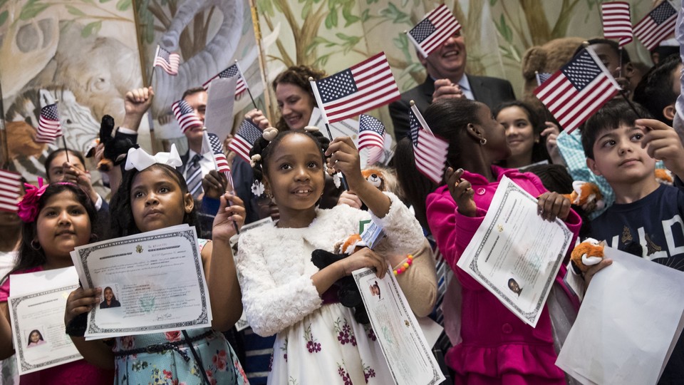 Children waving American flags and holding citizenship certificates