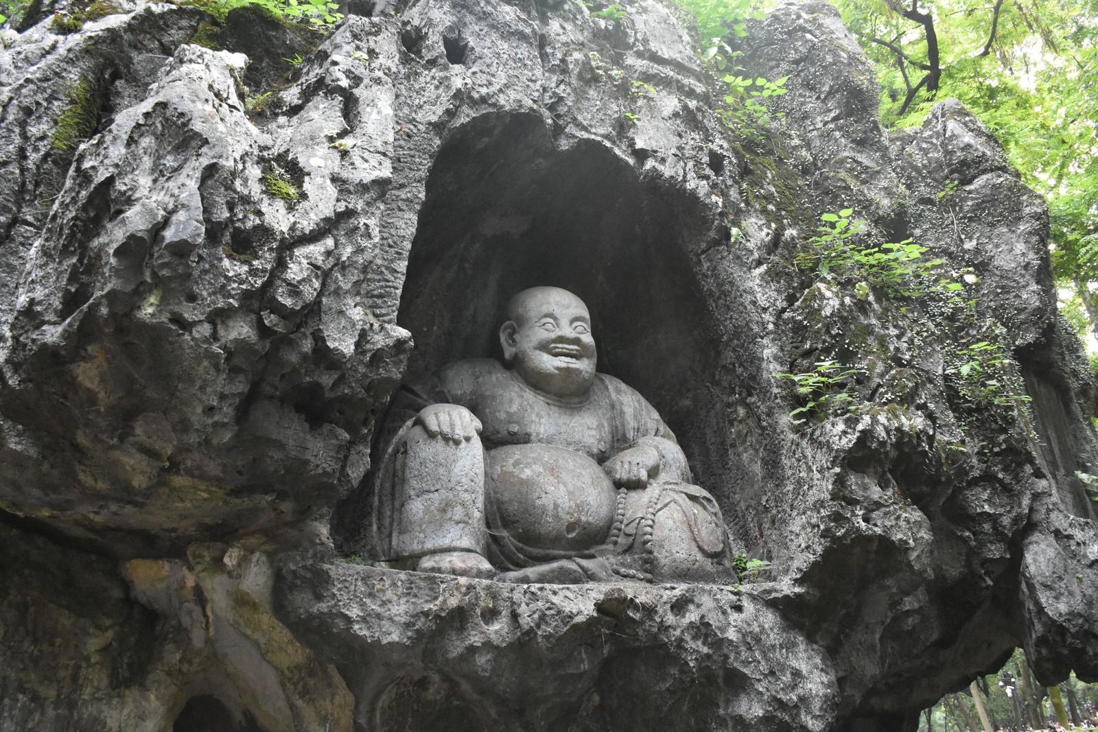 A small statue of Buddha, carved into a recess in a rock