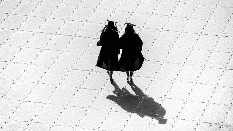 Two college graduates in cap and gown.