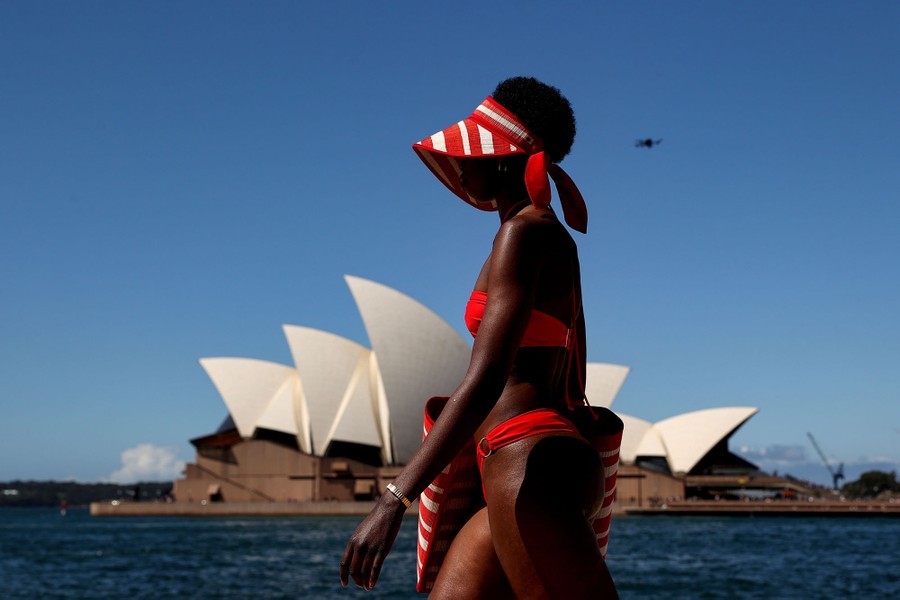 A model displays swimwear on an outdoor runway near the Sydney Opera House.