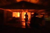 A firefighter surveys a burning house.