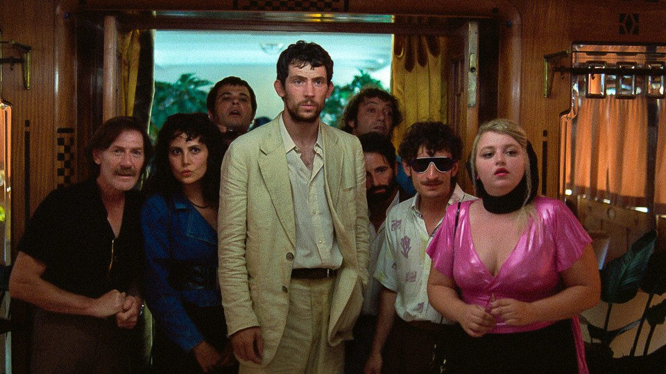 a group of people staring at something off camera, josh o'connor in the center