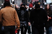 Masked and unmasked people, walking down a city street