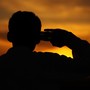 A boy salutes at sunset