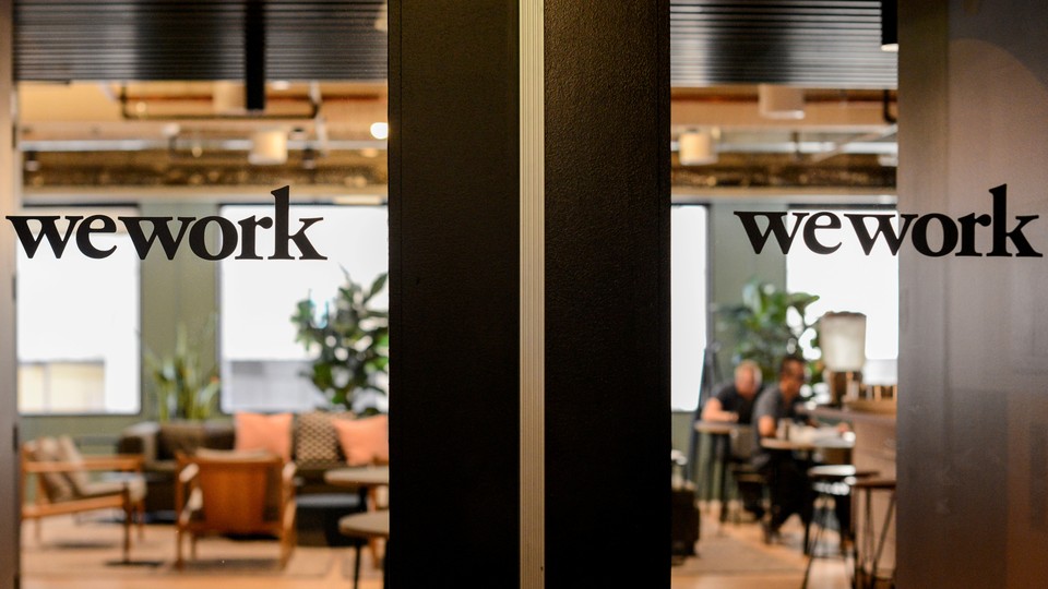 The WeWork logo is printed on a glass door, with an office visible behind it.