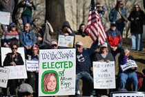 A group of protesters gather in North Carolina. One sign reads: We the People elected Allison Riggs for NC Supreme Court