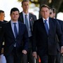 Sérgio Moro and Jair Bolsonaro walk with marines at a military ceremony.