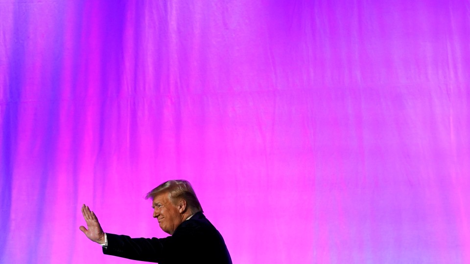 President Donald Trump waves in front of a pink background.
