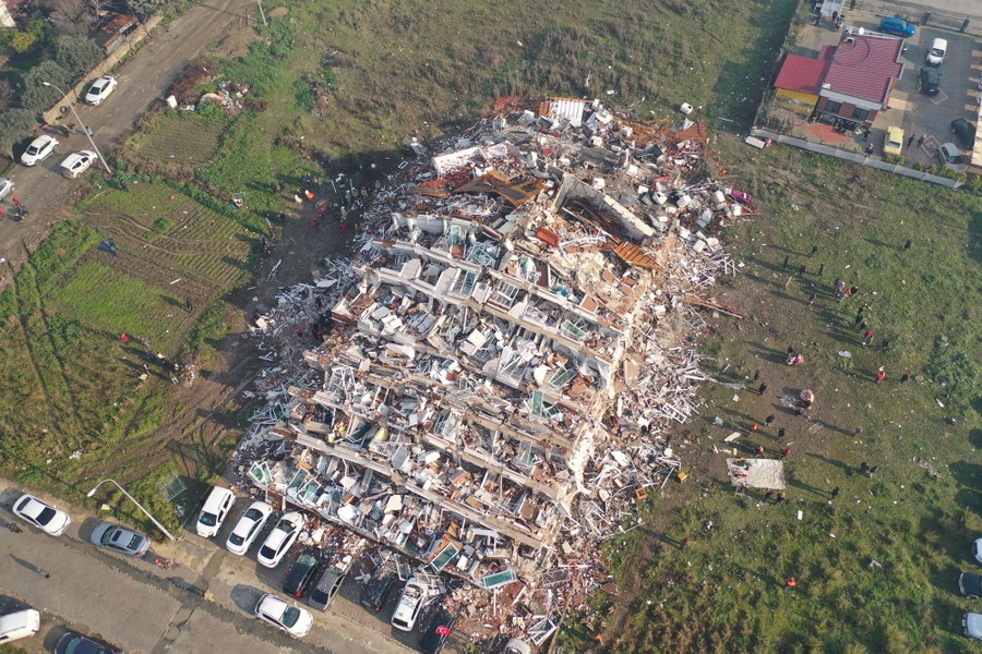 An aerial view of a multistory apartment building collapsed into a field