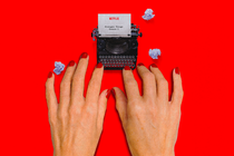 An illustration of a tiny typewriter being used by giant hands.