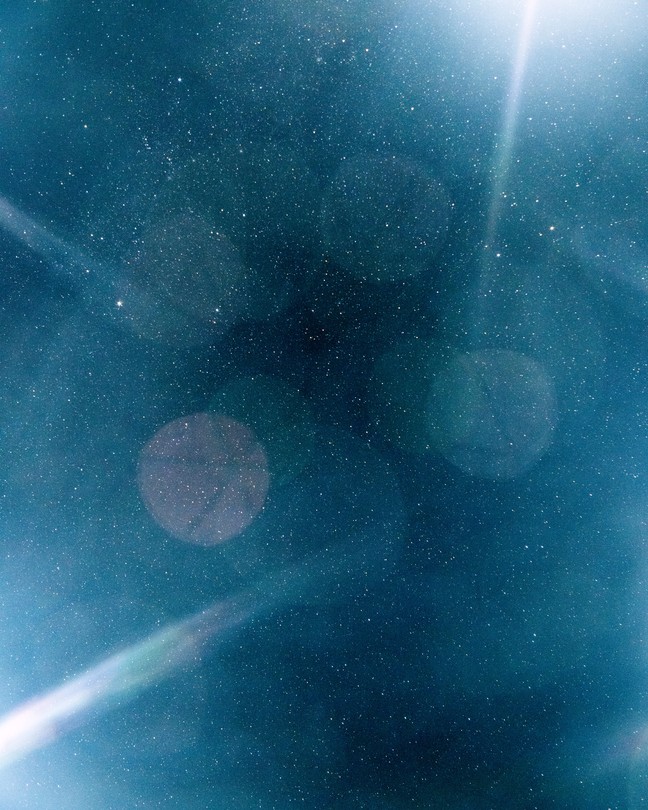 A photograph of a starry sky with beams of light