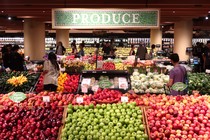 People walk through the produce department at a grocery store