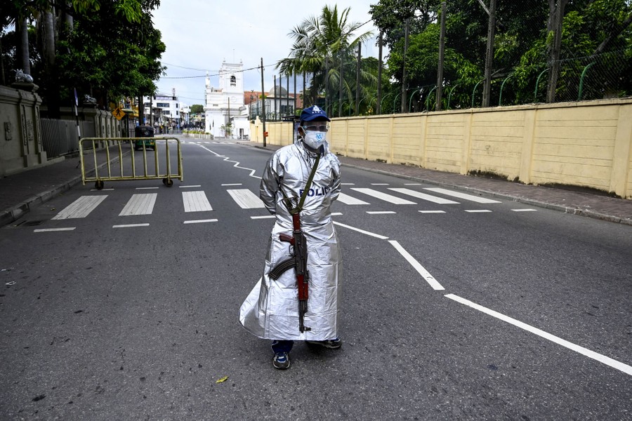 A policeman wearing a long silver uniform stands in a street.