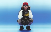 Billie Eilish crouching in plaid shorts and a red Jordan Jumpman cap