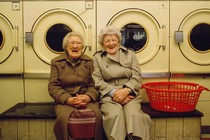 Two elderly women sitting at a laundromat