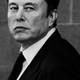 A black-and-white photo of Elon Musk in a suit and tie, looking back over his left shoulder.
