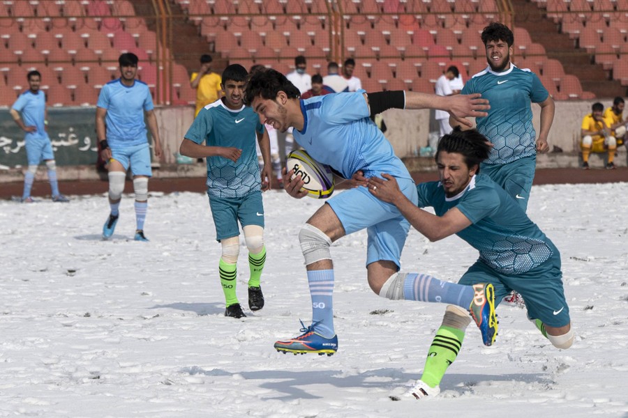 Young players take part in a rugby game on a snow-covered field.