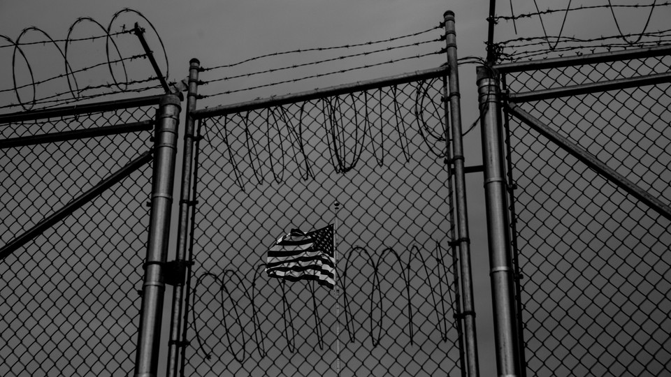 An American flag behind barbed wire fence