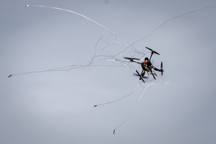A small drone, caught mid-air in a net, falls.