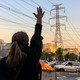Women raise their hands in protest in front of a burning dumpster during the 2022 demonstrations in Tehran