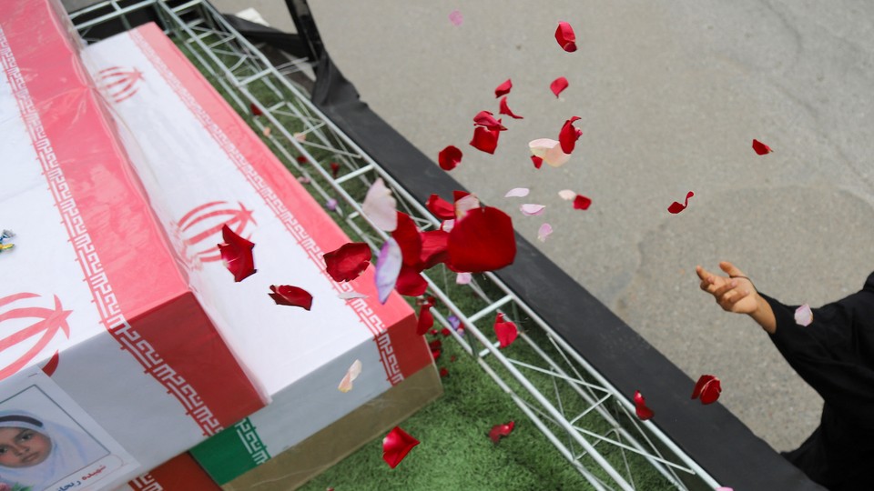 In this picture obtained from Iran's ISNA news agency, a mourner sprays flower petals on the coffins of children who were killed in a reported strike on a primary school in Iran's Hormozgan province during a funeral in Minab on March 3, 2026.