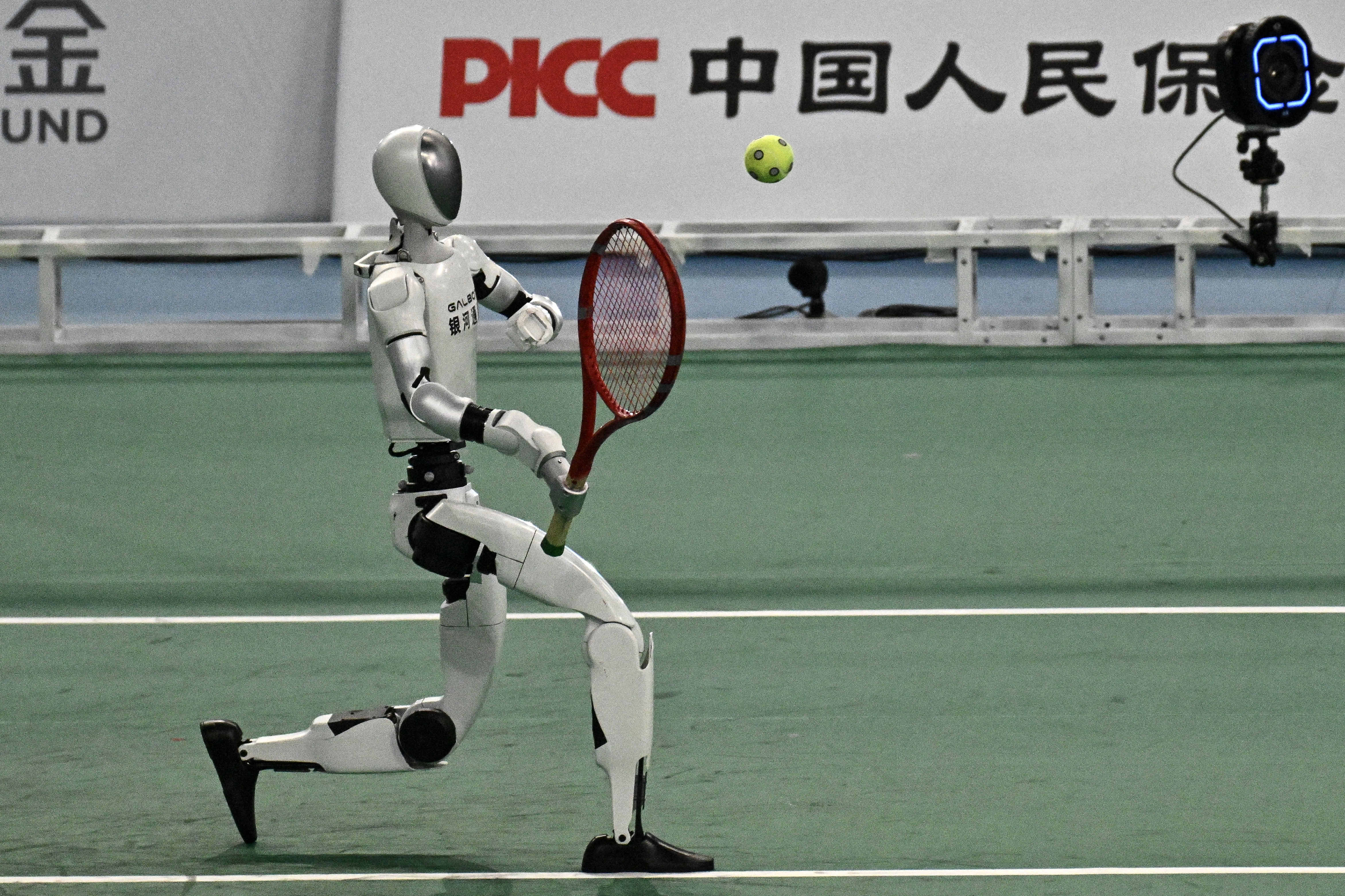 A humanoid robot returns a ball during a tennis match.