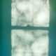 Light from a window on bright teal wall
