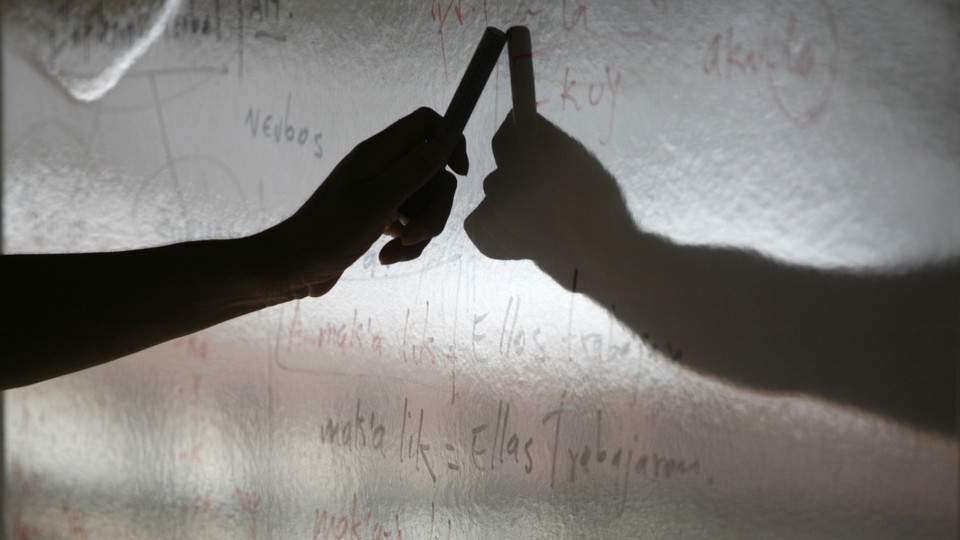 A hand hovers over a dry-erase board, casting a shadow.