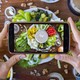 A person uses a smartphone to photograph a platter of vegetables and vegan mayonnaise.