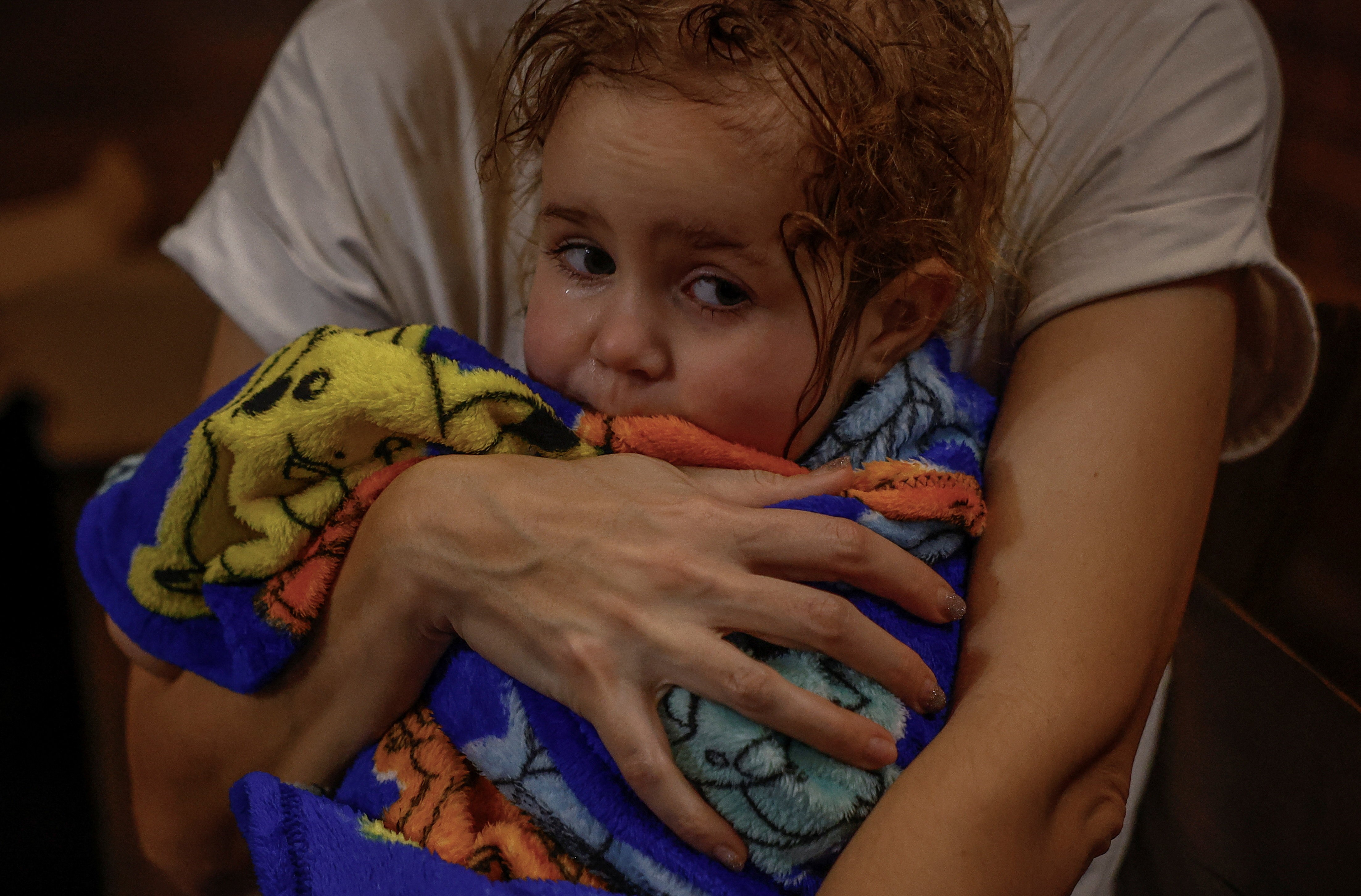 A woman holds her young daughter, wrapped in a towel.