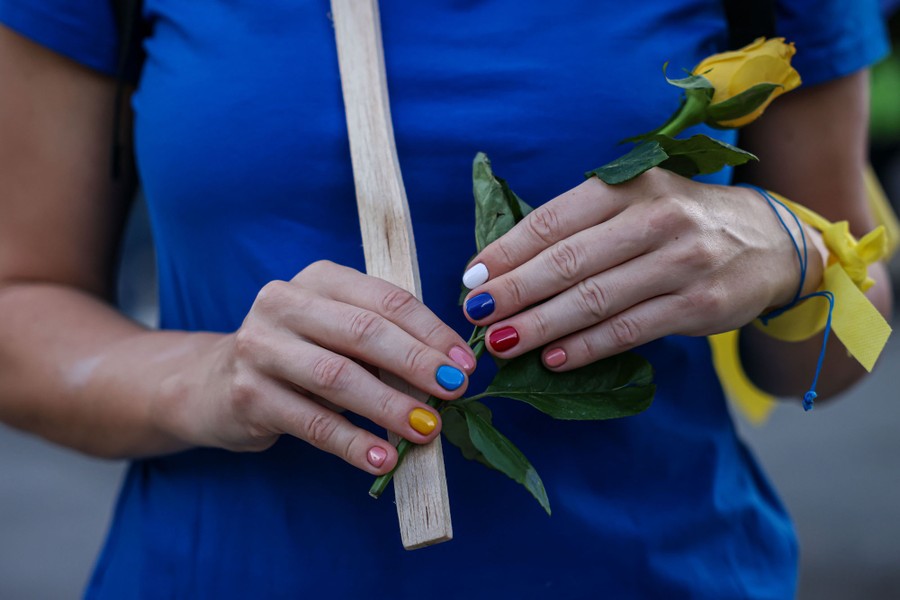 A close view of a person's hands, their nails painted in the colors of Russia's and Ukraine's flags.